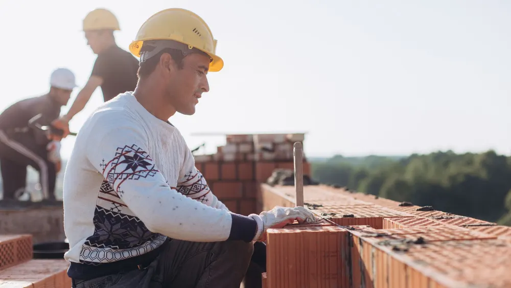 Maçon montant un mur en briques sur un chantier