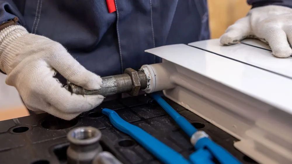 Plombier raccordant un tuyau de radiateur sur un chantier