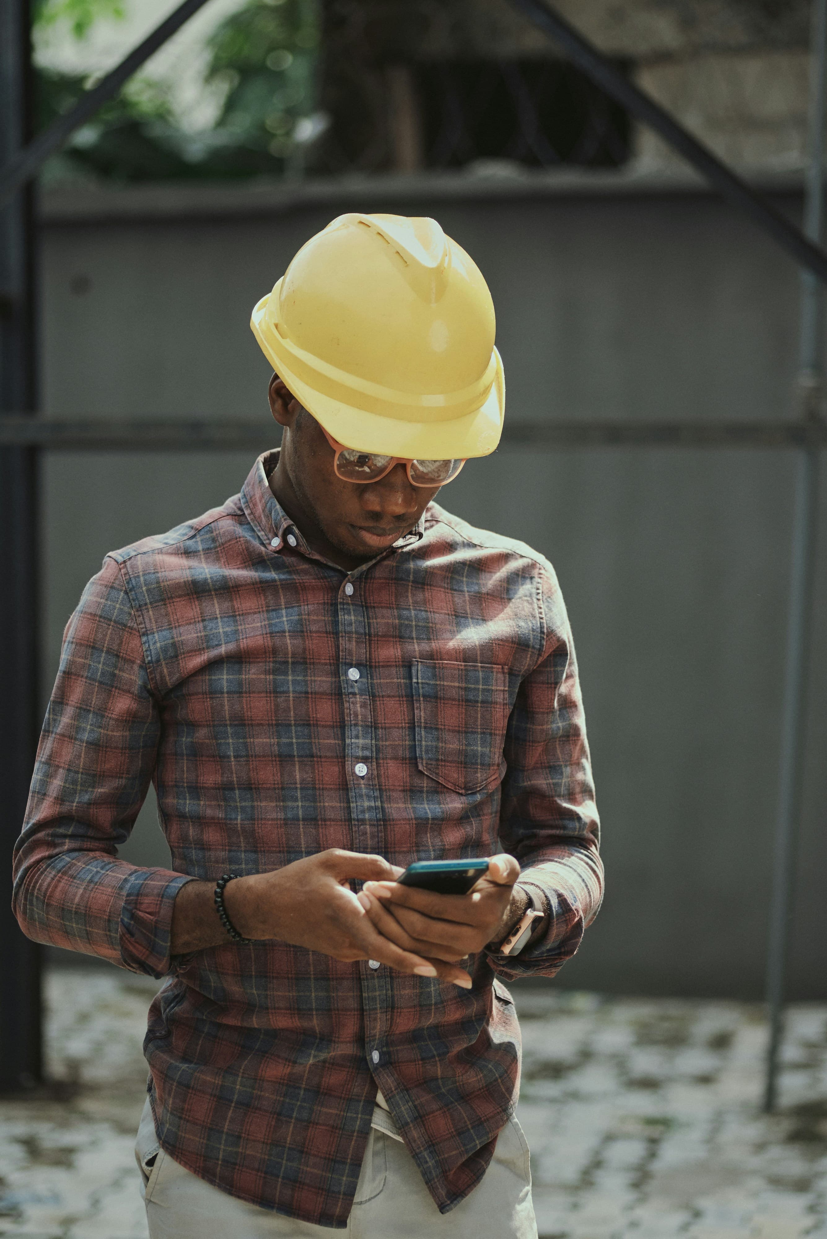 Artisan en casque de chantier qui prépare un devis sur son téléphone