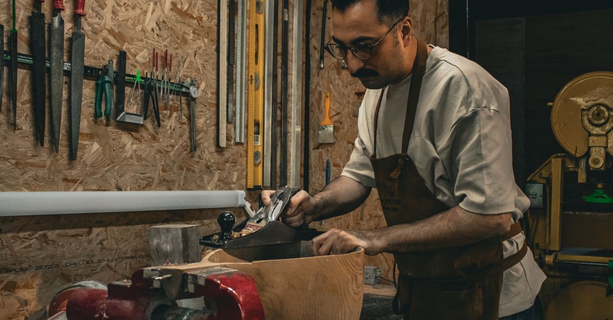 Artisan menuisier façonnant une pièce de bois à l'outil à main dans son atelier