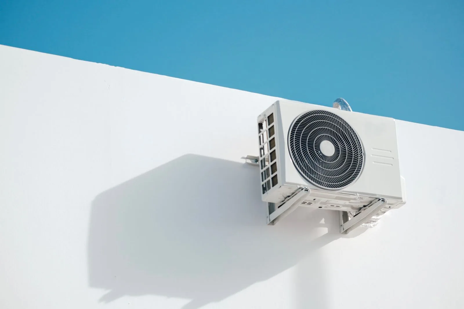 Unité extérieure de climatisation fixée sur un mur blanc