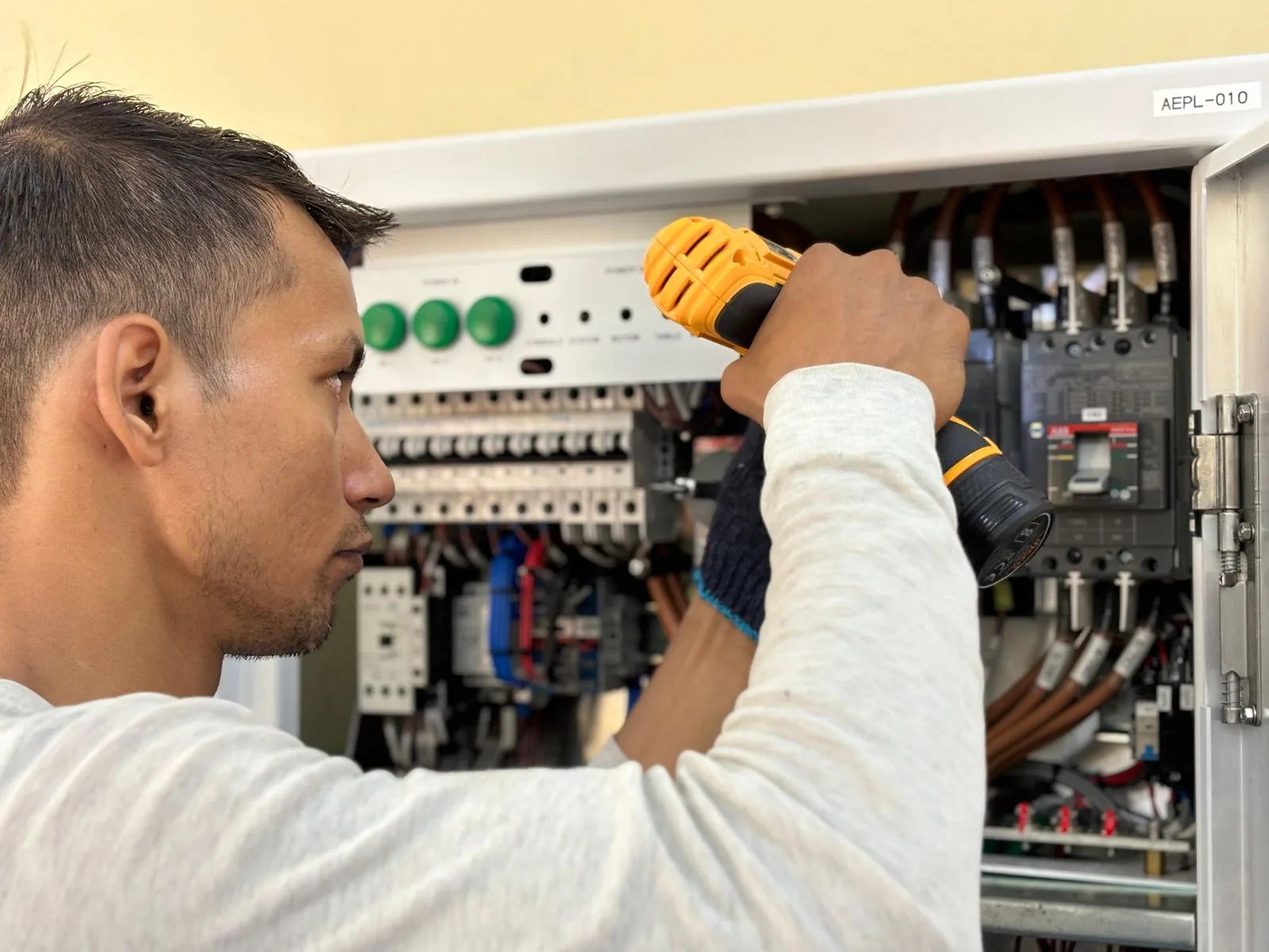 Électricien qui visse une protection dans un tableau électrique ouvert