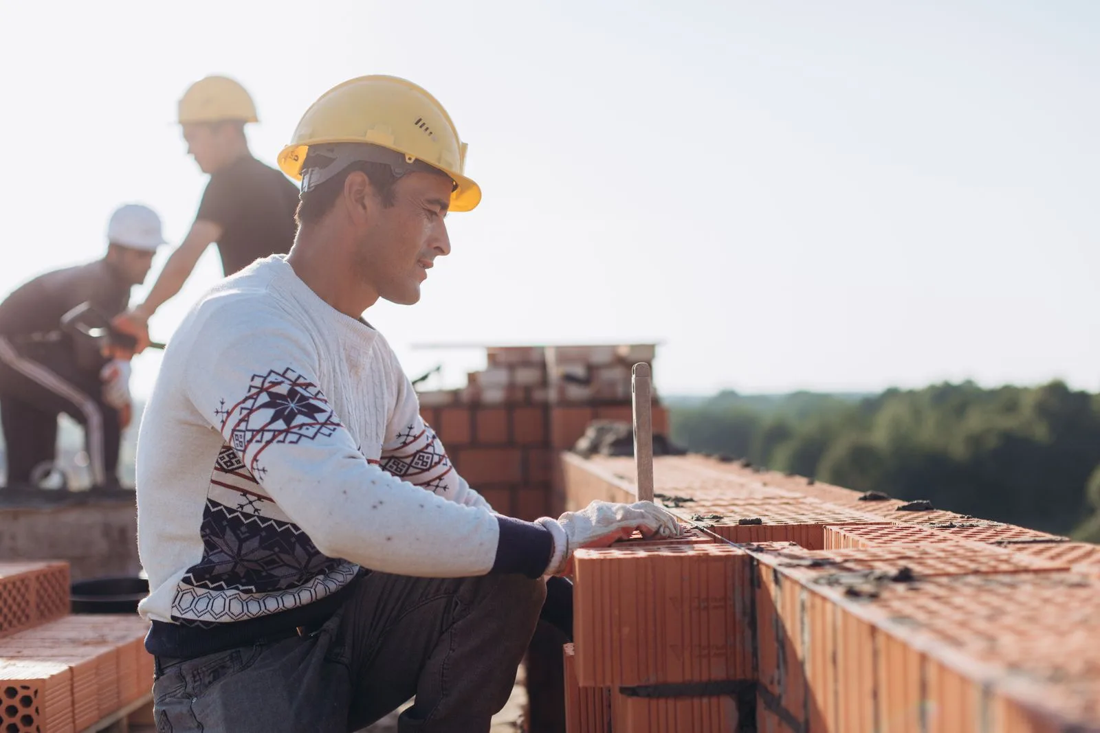 Maçon en casque qui monte un mur en briques sur un chantier