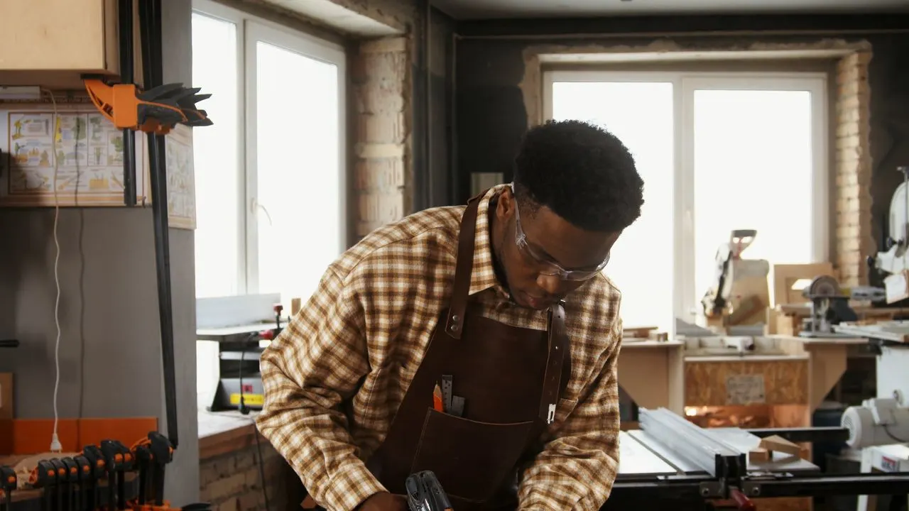 Menuisier au travail dans son atelier, tablier de cuir