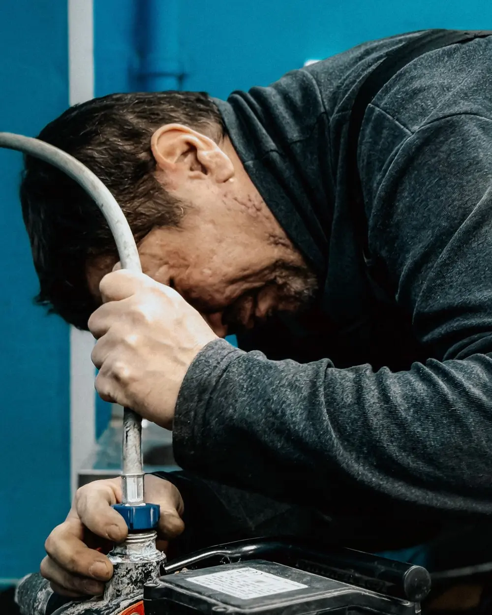 Plombier penché sur une pompe à eau, en train de serrer un raccord flexible